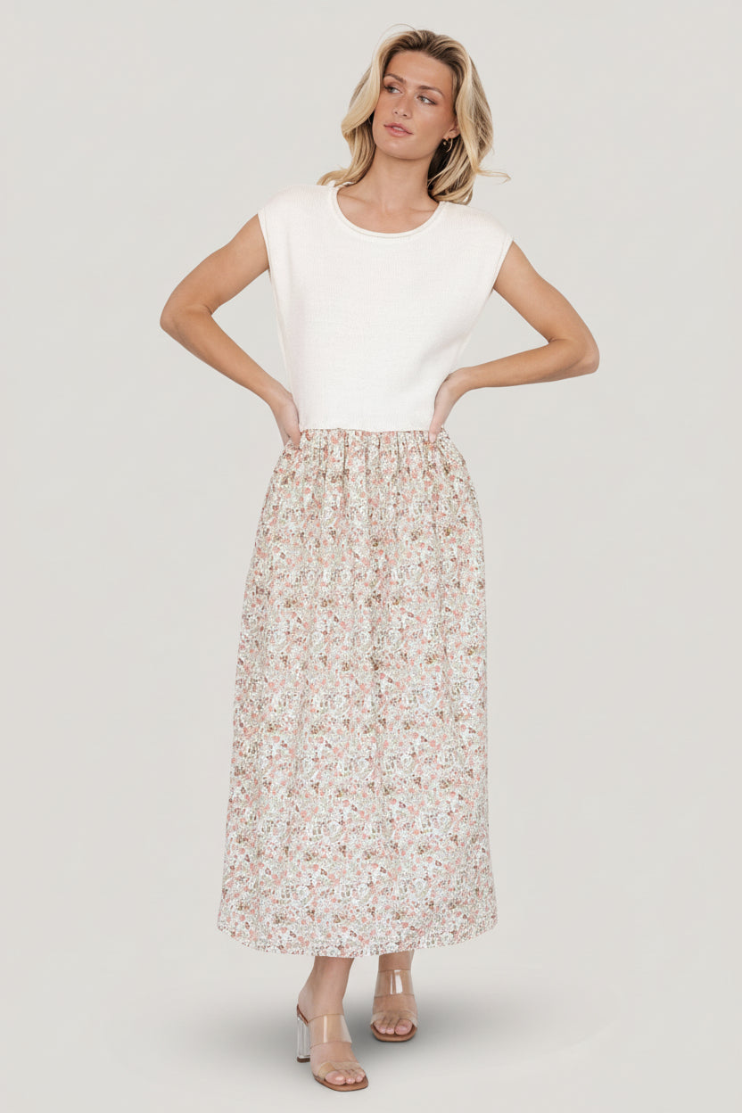 Front view of Myra sweater dress in ivory with coral, blue and green floral print, short cap sleeves and elastic waist, pockets visible.