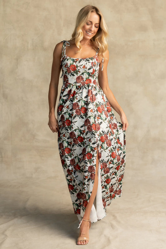 Nadine Maxi Dress in Red + Green Floral with tie straps, smocked back, flowing skirt, and left leg slit.