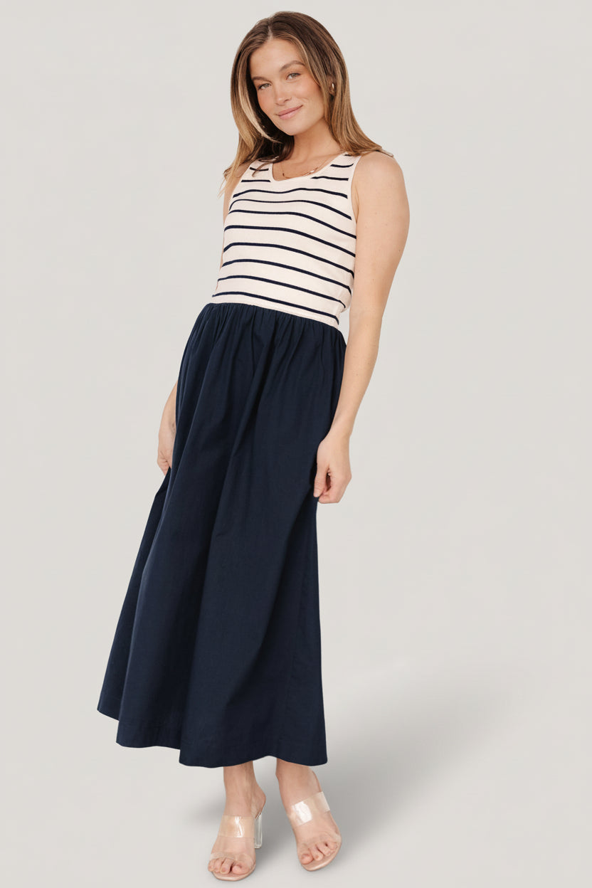 Full-length image showing the navy stripe dress styled with sandals, emphasizing midi length, movement, and casual coastal aesthetic.