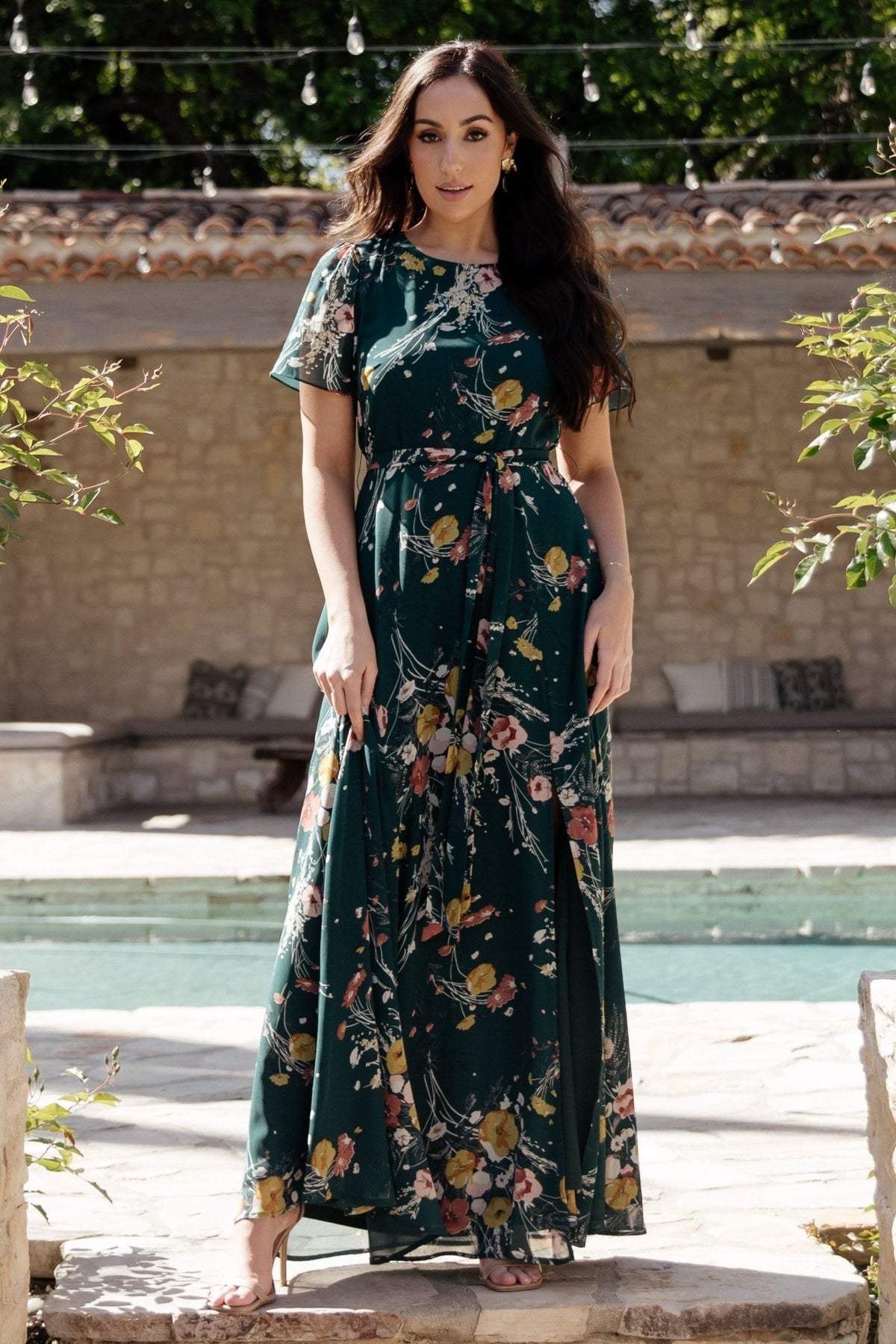 Three-quarter view of dark green floral maxi dress highlighting bodice shape, keyhole back closure, and flowing chiffon skirt.