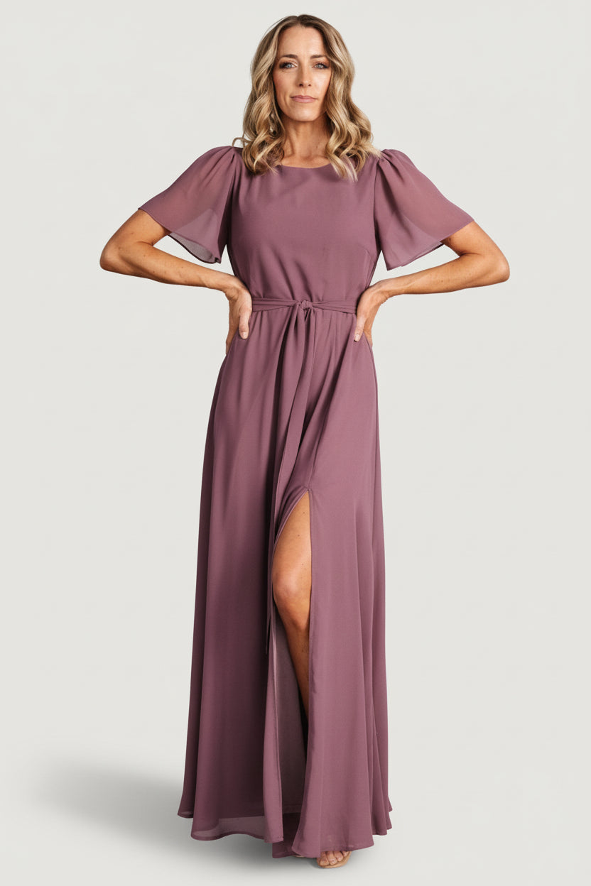 Front view of Naomi chiffon maxi dress in vintage plum on model, rounded neckline, removable waist tie, and flowing skirt sweeping to maxi length.