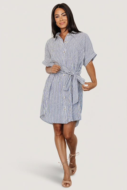 Front view of a blue-and-ivory striped seersucker shirt dress with collared neckline, button-front placket and self-tie sash for waist shaping, on white background.