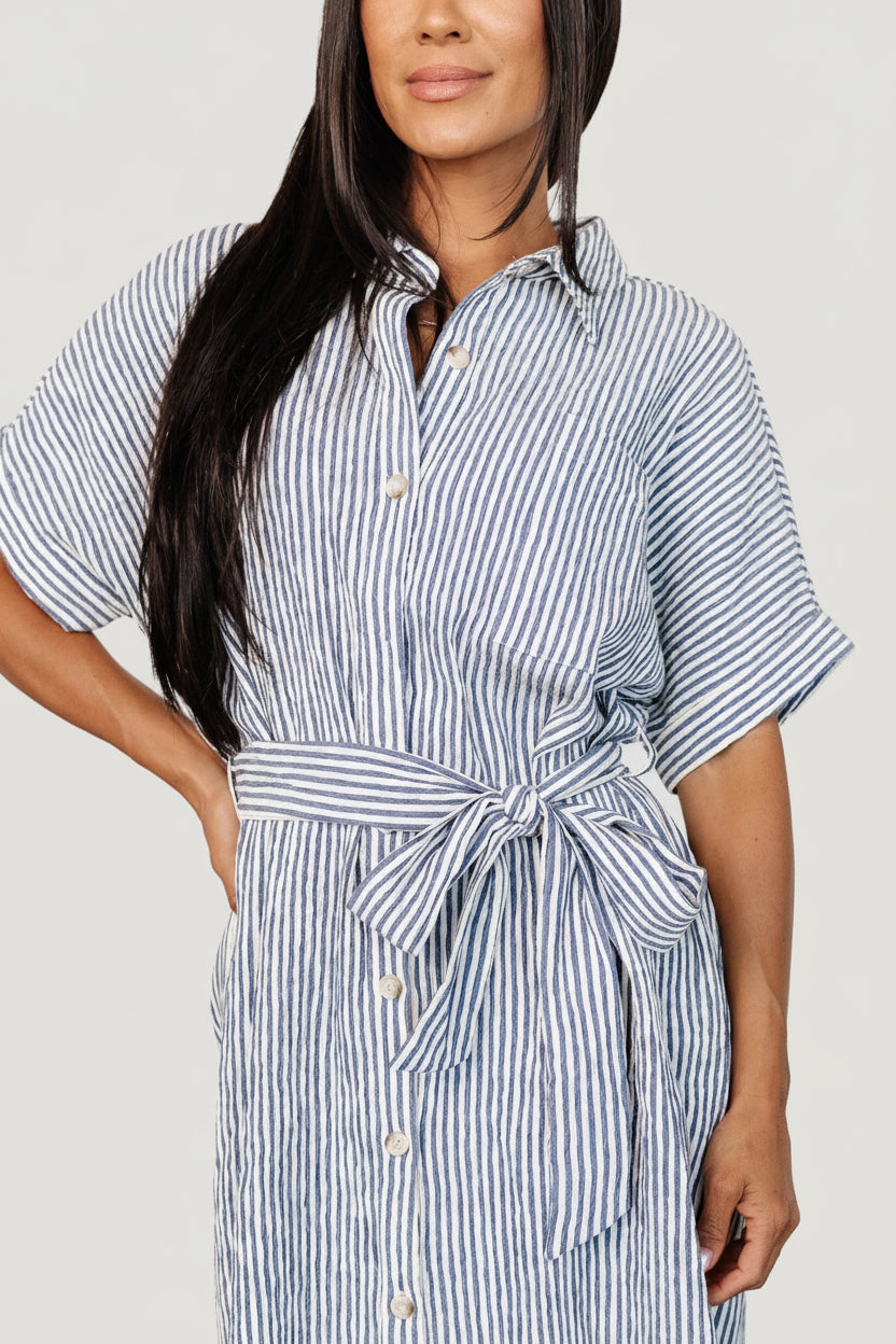 Back view of the blue-and-ivory striped tunic shirt dress, showing collar, back yoke, and subtle stretch in the seersucker fabric for comfort.
