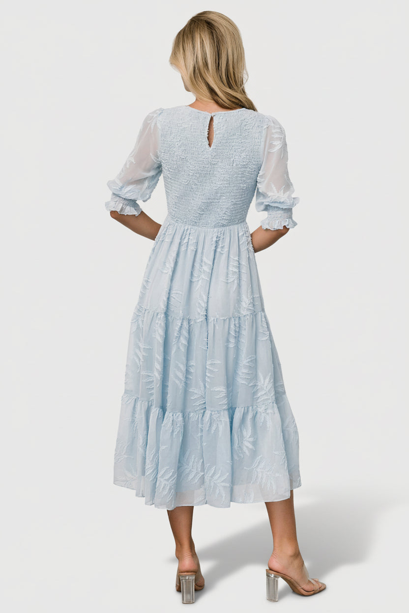Side profile of Nellie Smocked Midi Dress in light blue chiffon, showing sleeve silhouette, tiered skirt movement, and lined interior.
