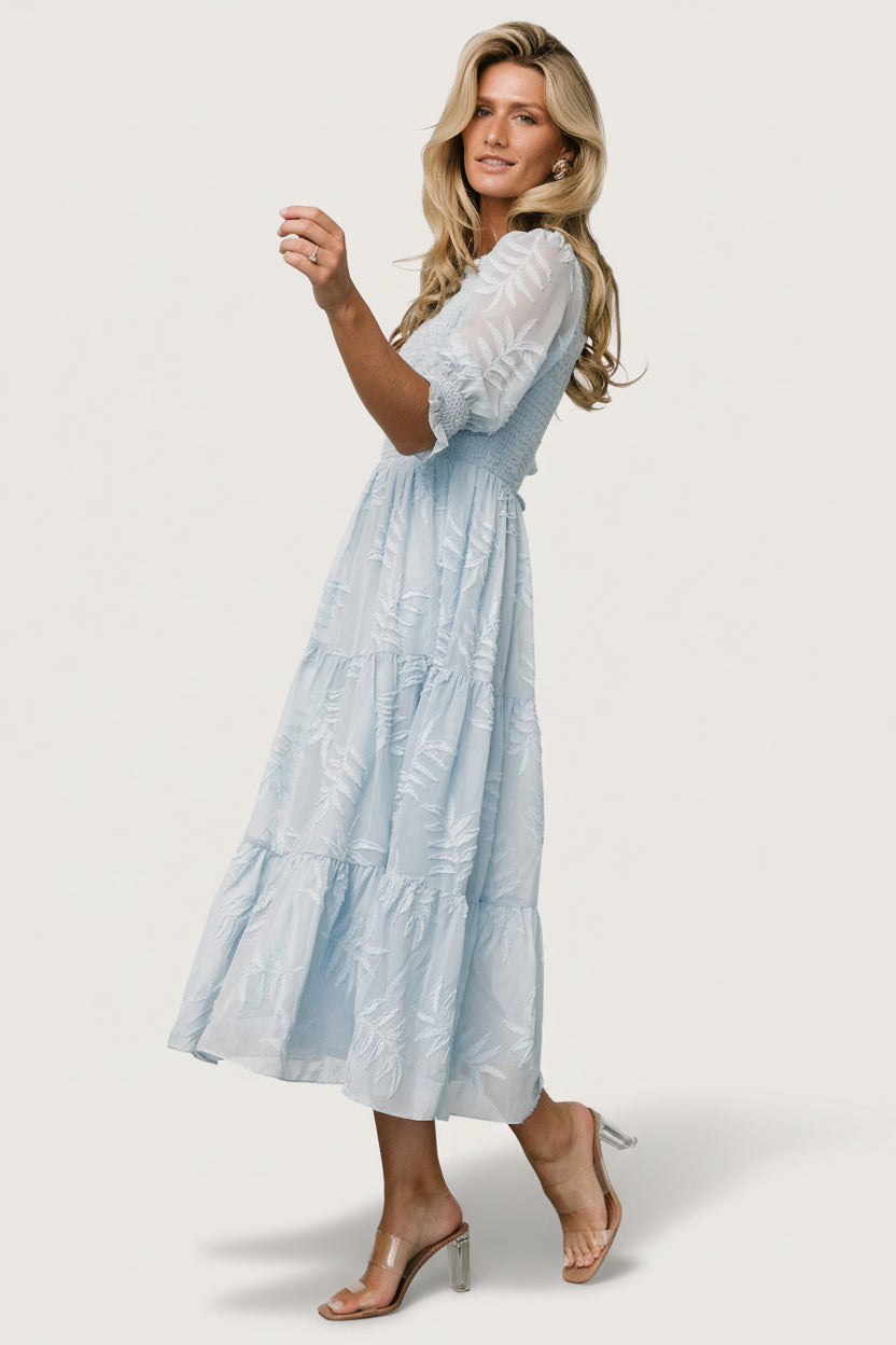 Lifestyle image of the Nellie Smocked Midi Dress styled for daytime events, showcasing soft chiffon fabric, burnout botanical print, and midi length.