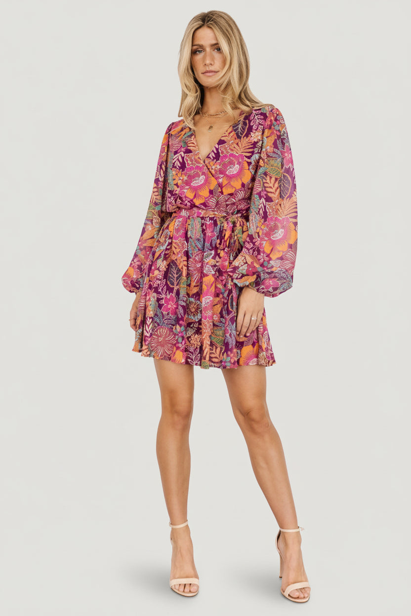 Model walking in Newark mini dress, long sleeves softly gathered at cuff and A-line flare skirt movement in purple multi floral pattern.