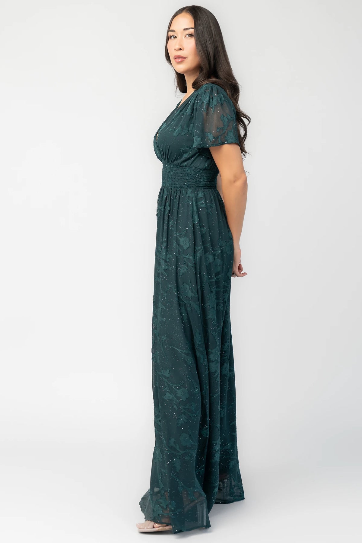 Noelle Maxi Dress in Dark Green Floral with silver sparkle, deep V-neck, flutter sleeves, smocked waist, and flowy skirt.