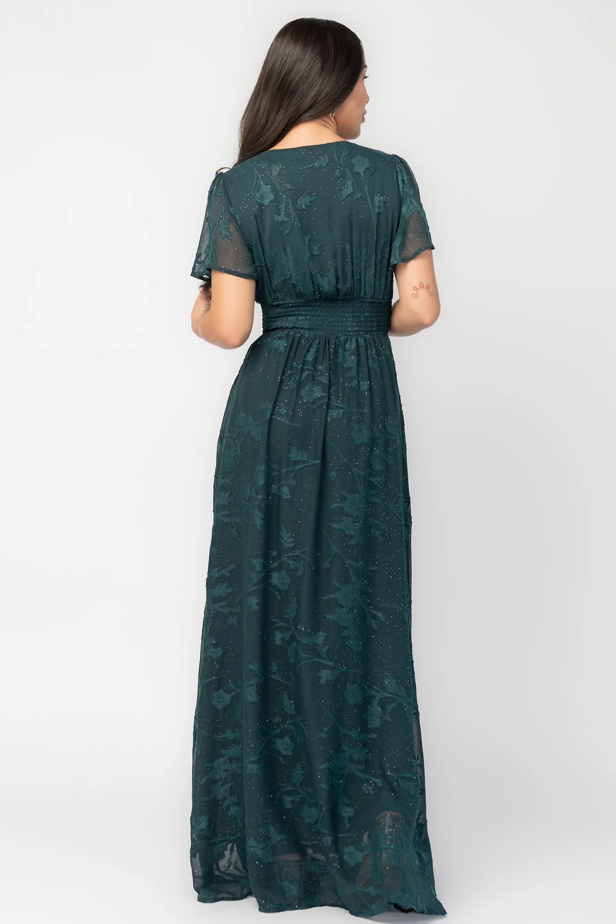 Noelle Maxi Dress in Dark Green Floral with silver sparkle, deep V-neck, flutter sleeves, smocked waist, and flowy skirt.