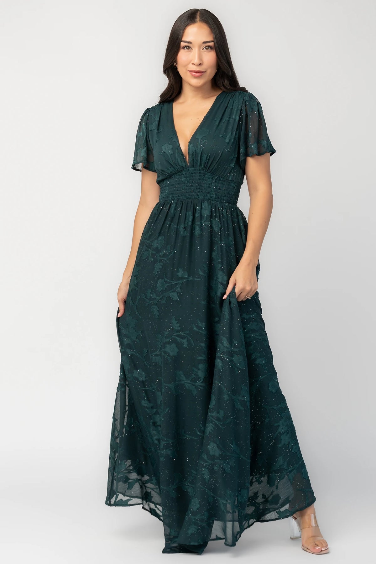 Noelle Maxi Dress in Dark Green Floral with silver sparkle, deep V-neck, flutter sleeves, smocked waist, and flowy skirt.
