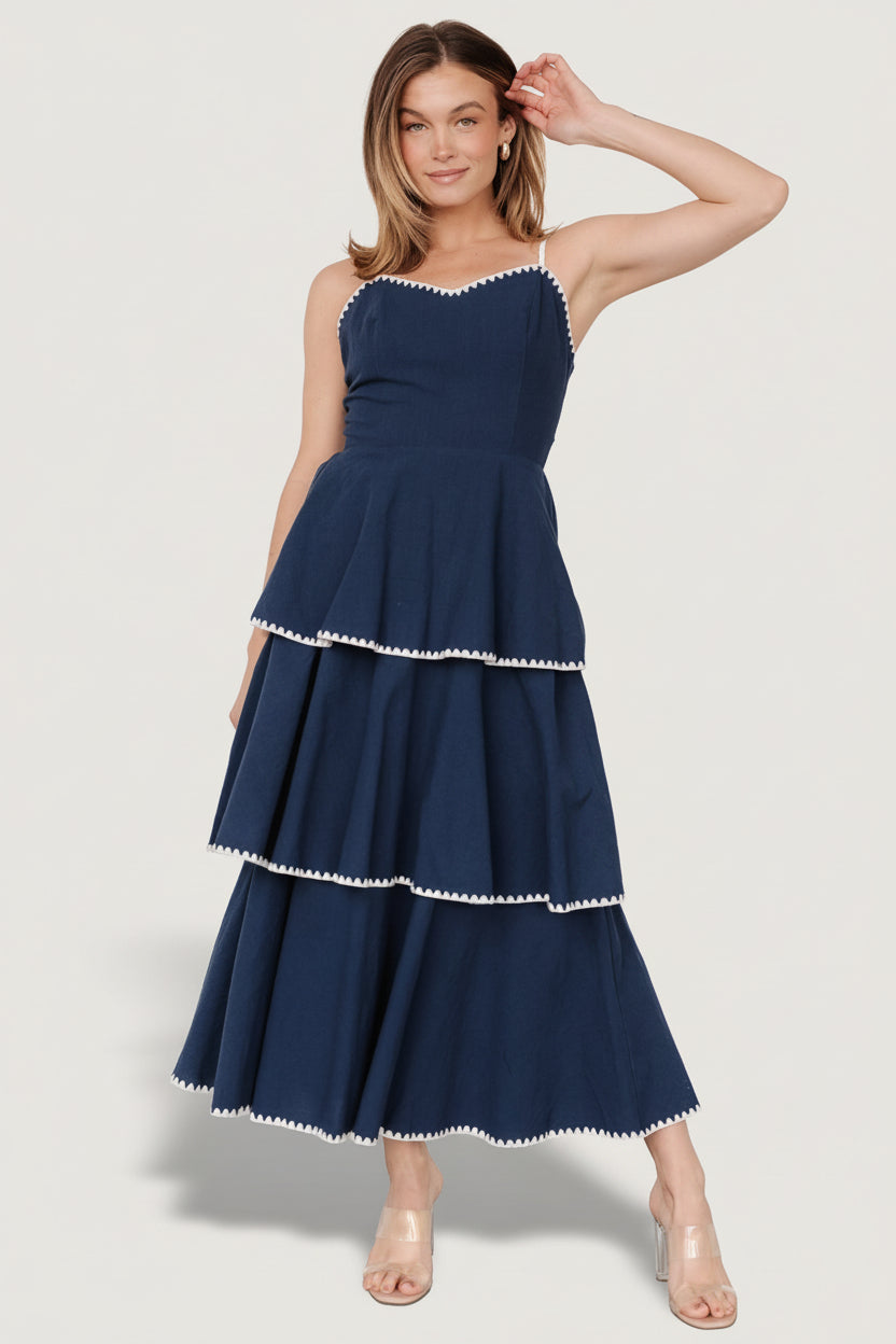 Front view of navy-and-white Odette tiered midi dress showing V-neckline, embroidered triangle accents, and overlapping tiers for movement.