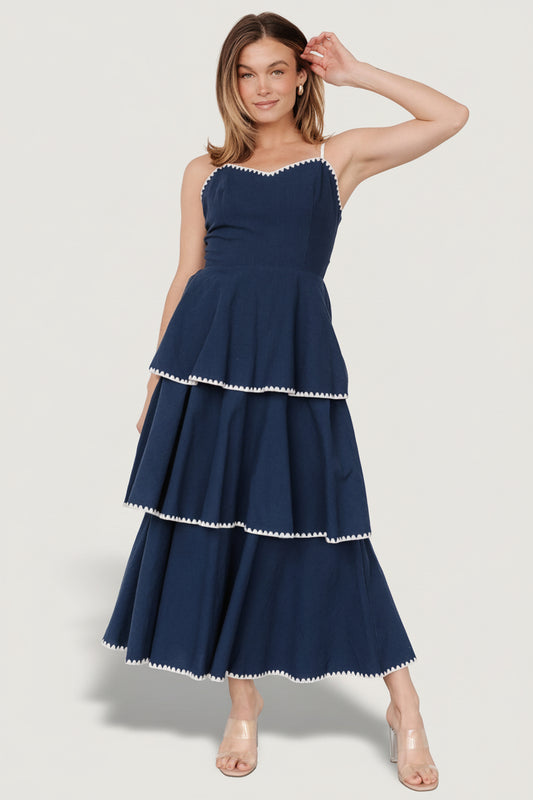 Front view of navy-and-white Odette tiered midi dress showing V-neckline, embroidered triangle accents, and overlapping tiers for movement.