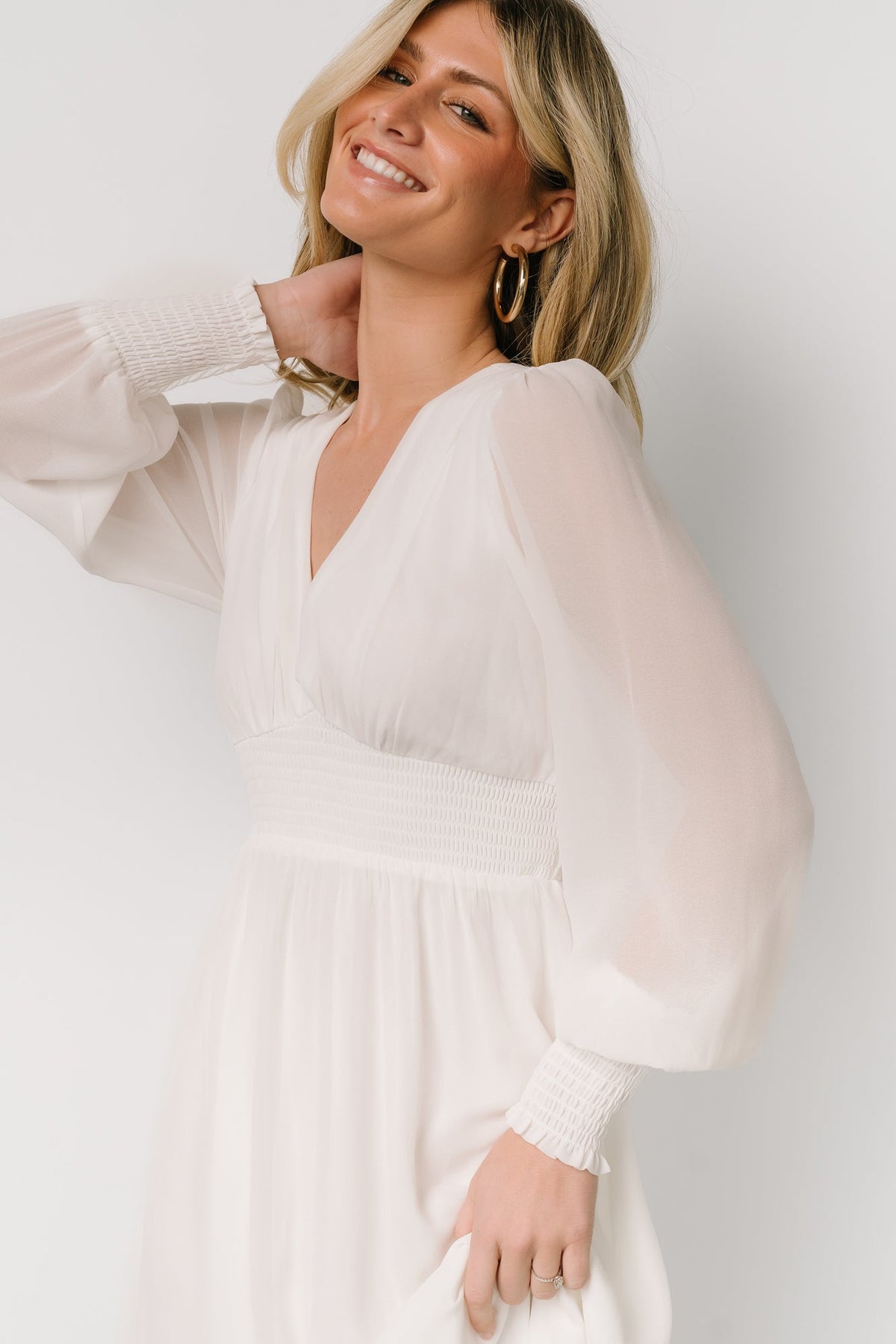 Lifestyle image of the Olivia Maxi Dress in white on model walking outdoors, showcasing full skirt sweep, smocked waist, and romantic silhouette.
