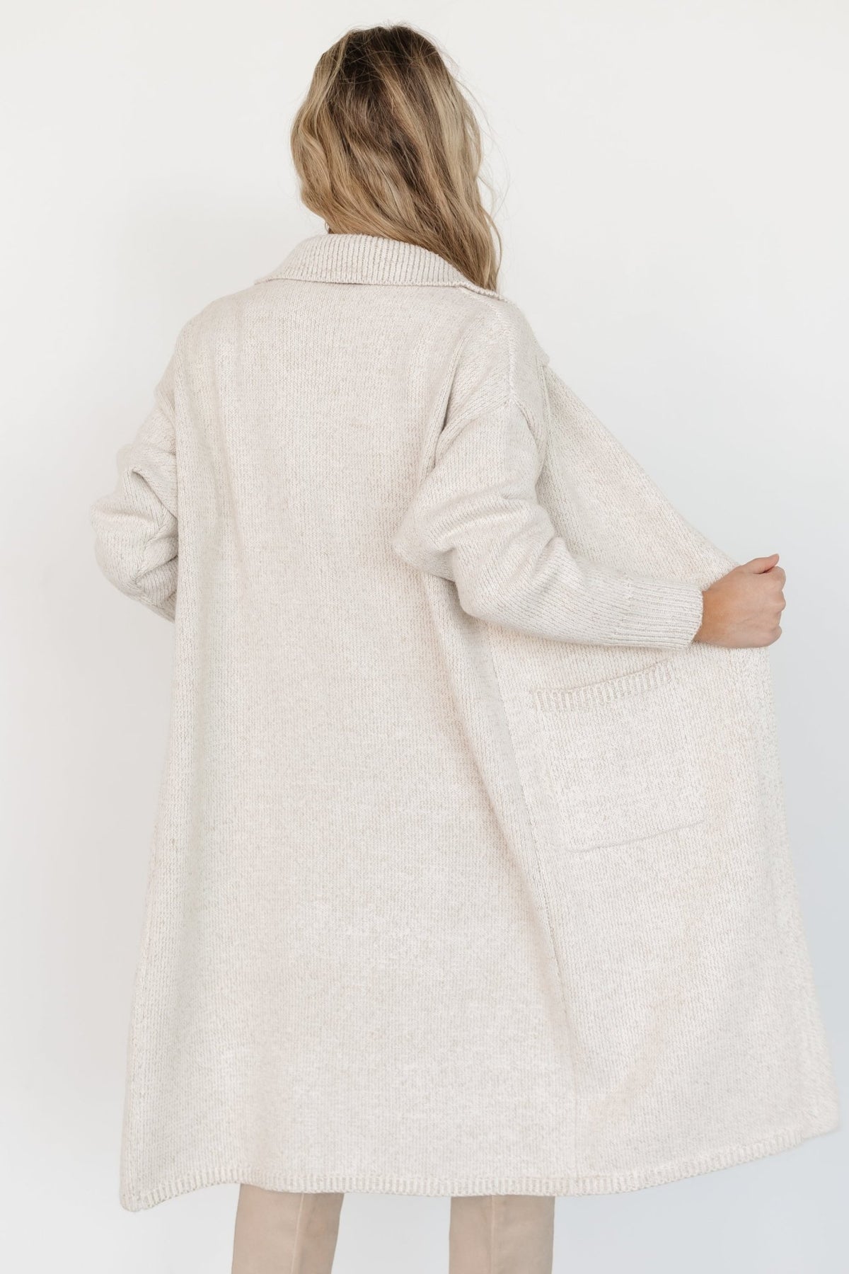 Lifestyled image of oatmeal longline cardigan worn with jeans, showing practical pockets, wide collar, and everyday layering appeal.