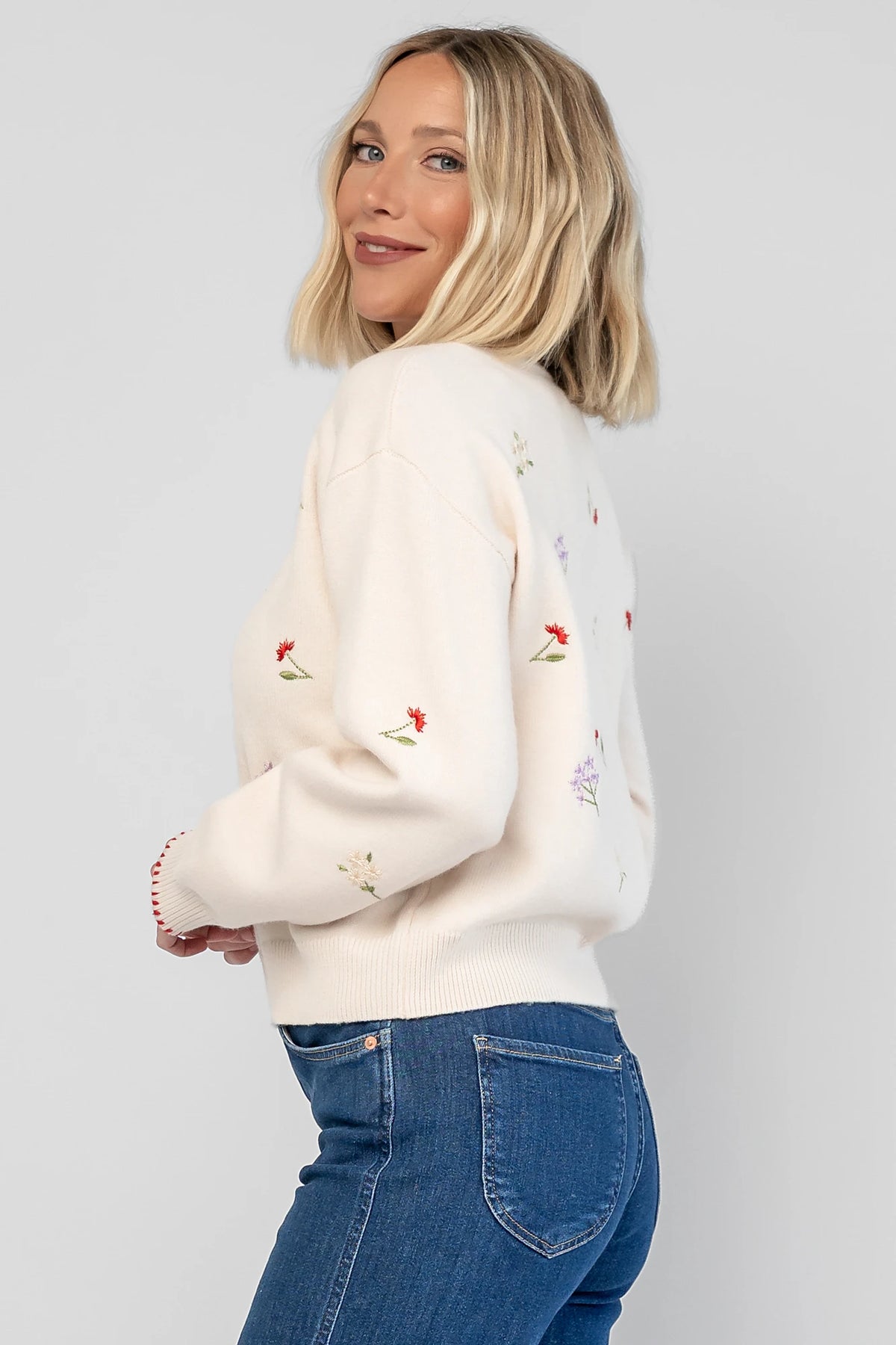 Ottilie Sweater in Cream with embroidered floral details, round neckline, red knit piping, and long sleeves.
