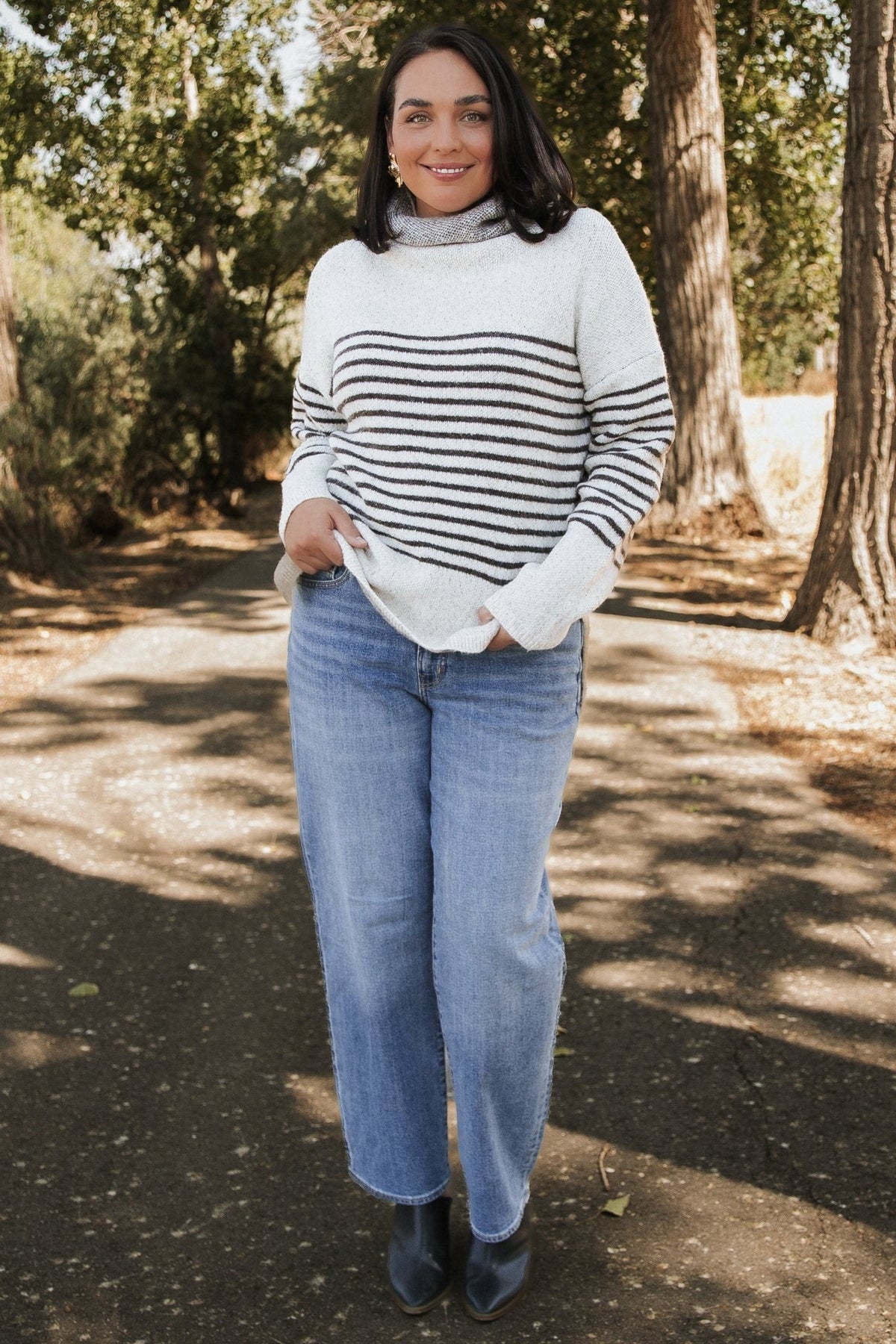 Front model view of Pennington turtleneck sweater in speckled cream with dark multi-stripes, ribbed cuffs and split side hem.