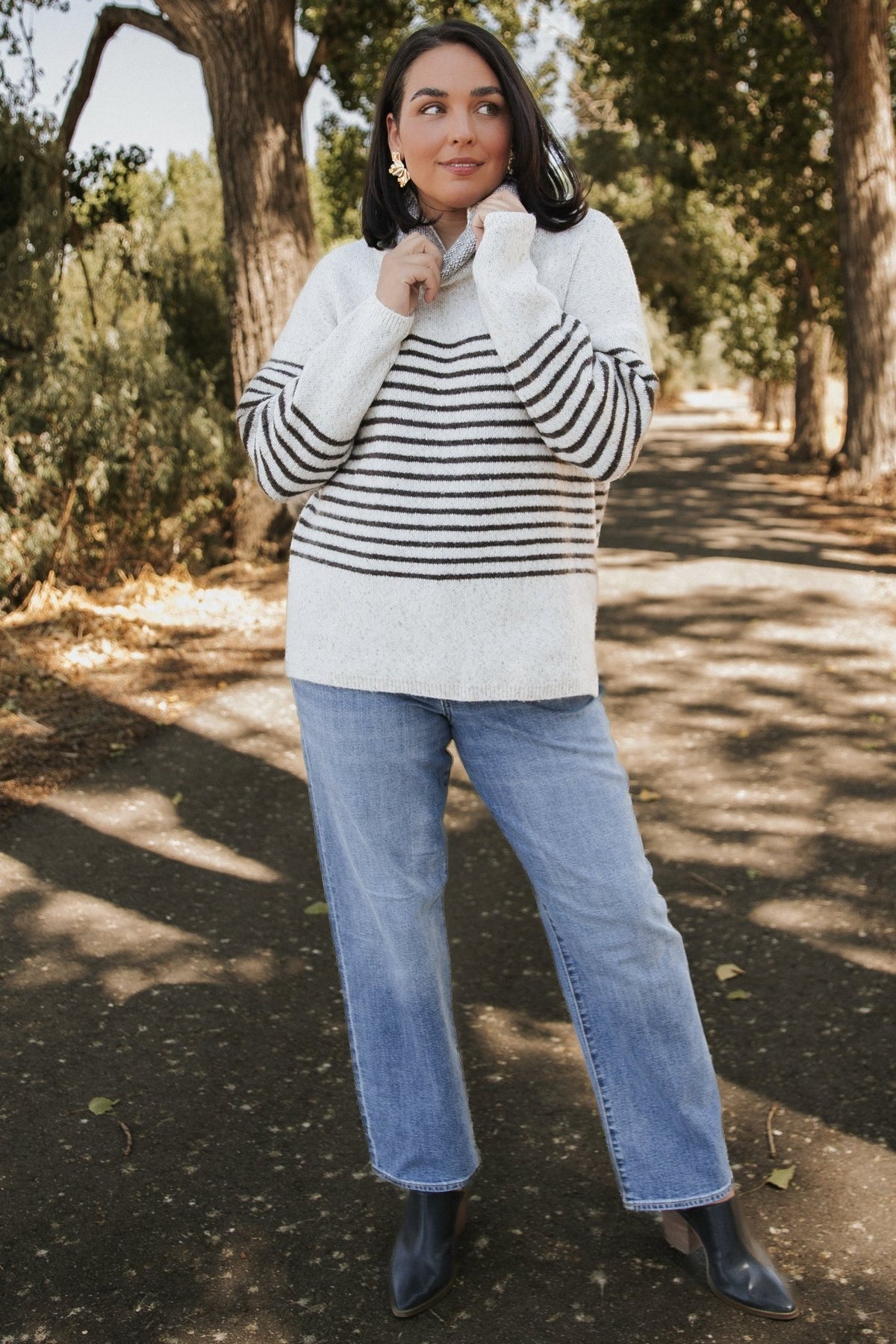 Front model view of Pennington turtleneck sweater in speckled cream with dark multi-stripes, ribbed cuffs and split side hem.