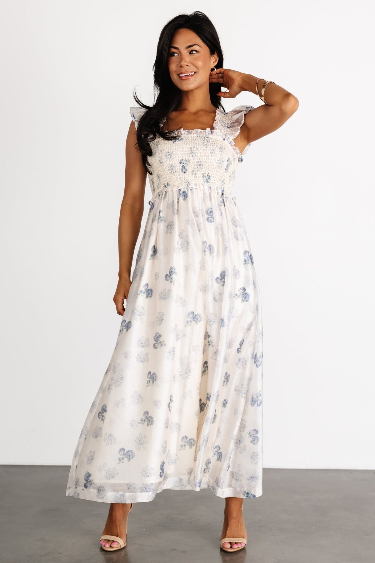 Side view of cream and blue floral midi dress on a model, showing tank ruffle sleeve detail and gentle a-line silhouette to mid-calf length.