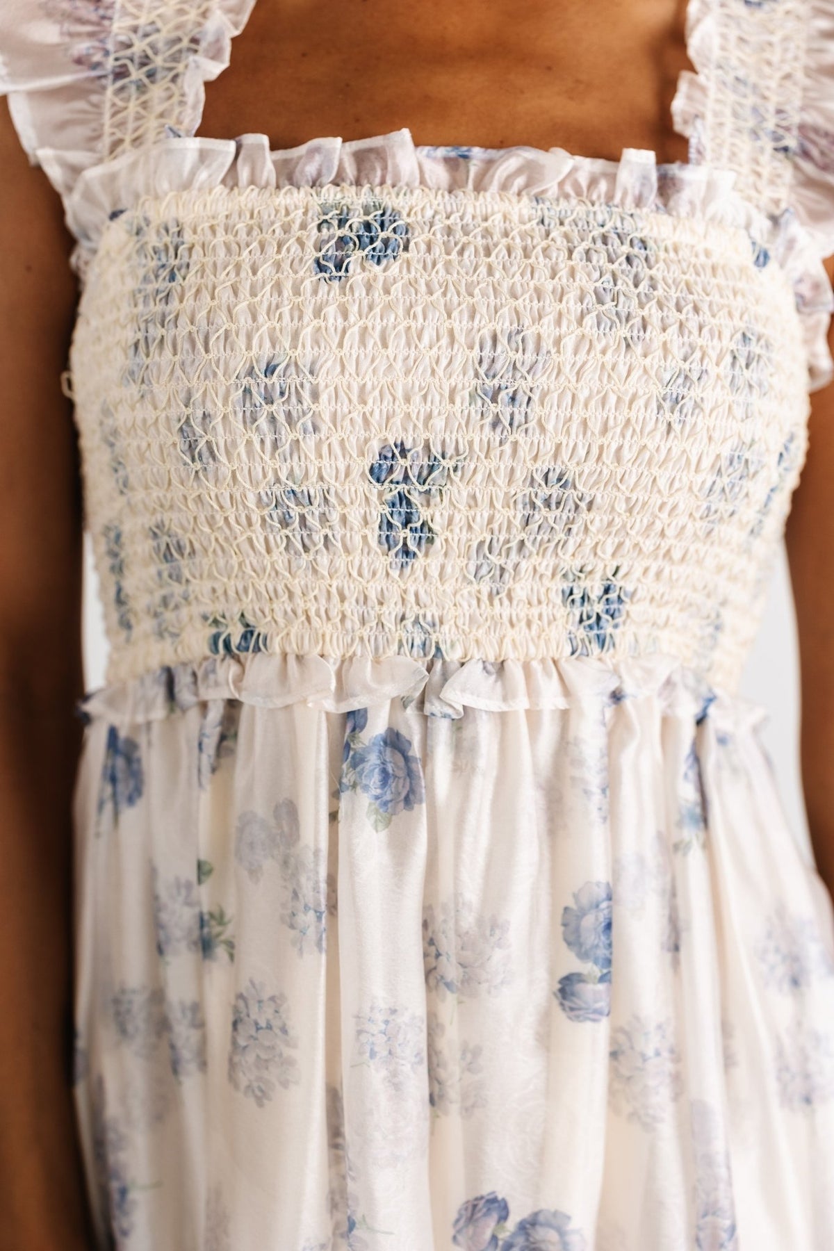Detail image of the lined skirt and hem of the cream midi dress, showing fabric drape and floral pattern in soft lighting.