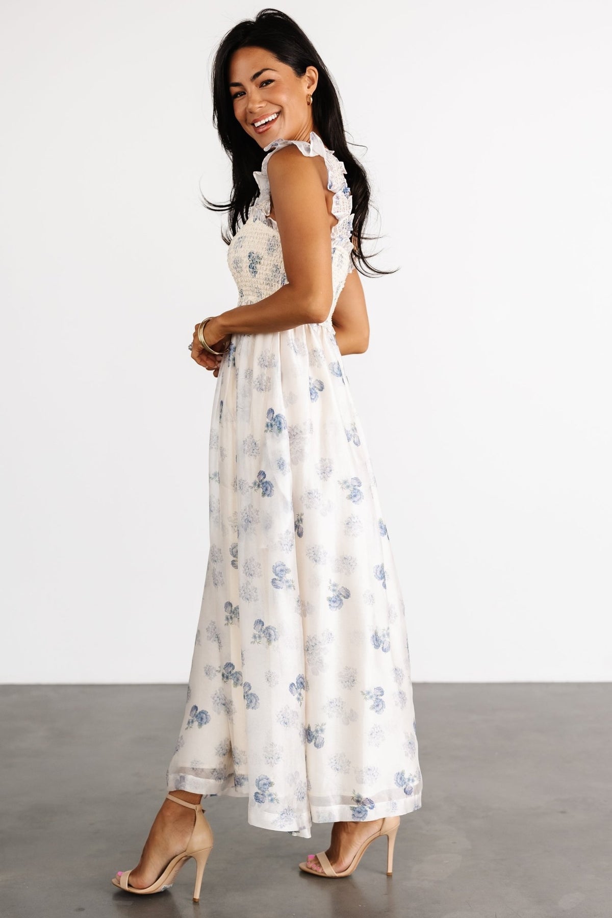 Back view of the cream floral midi dress on a model, showing the smocked back, fitted bodice, and mid-calf length silhouette.