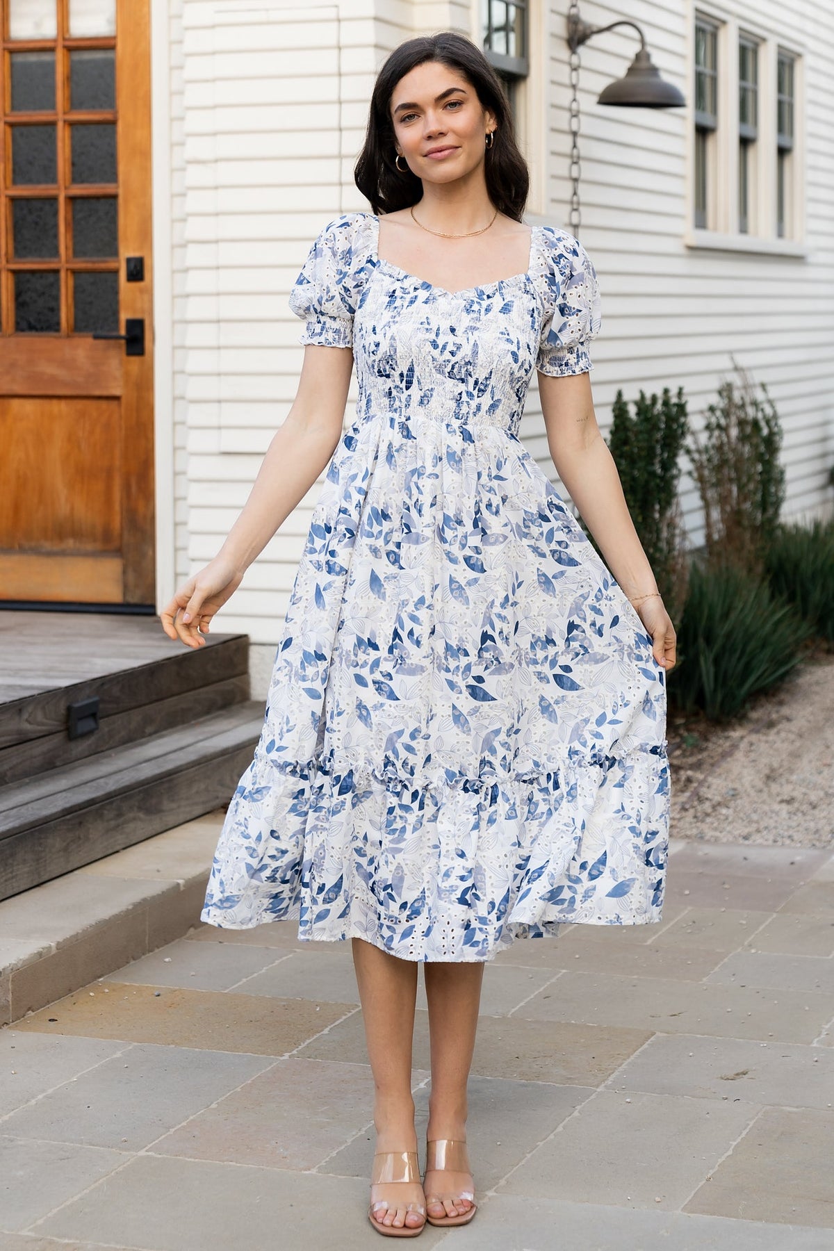 Front view of off-white midi dress with blue floral eyelet embroidery, smocked bodice and ruffled sweetheart neckline, midi skirt.