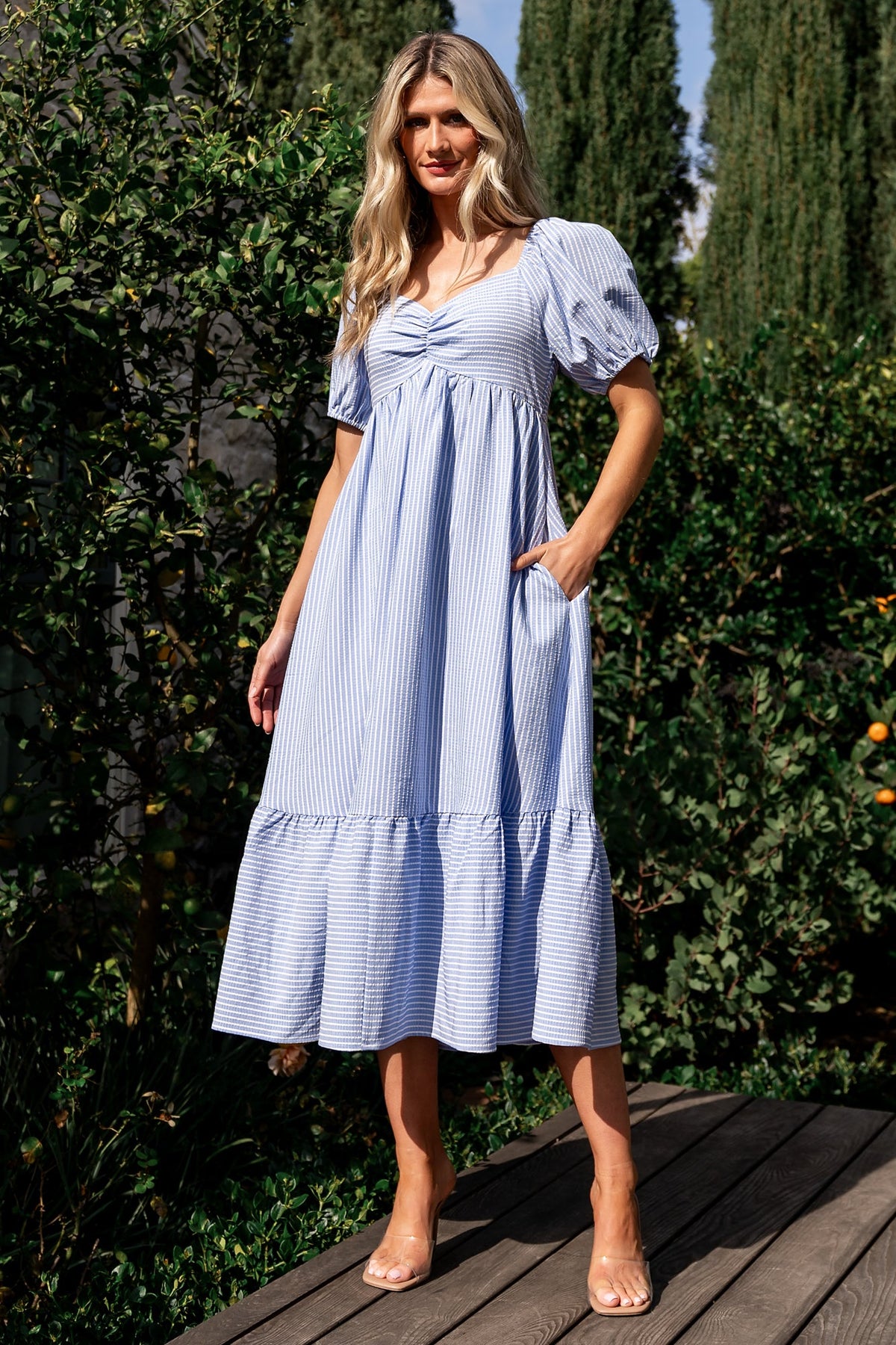 Side-angle image of the dress showing the upward-pointed empire waist, single-tier skirt, and discreet side pocket placement.