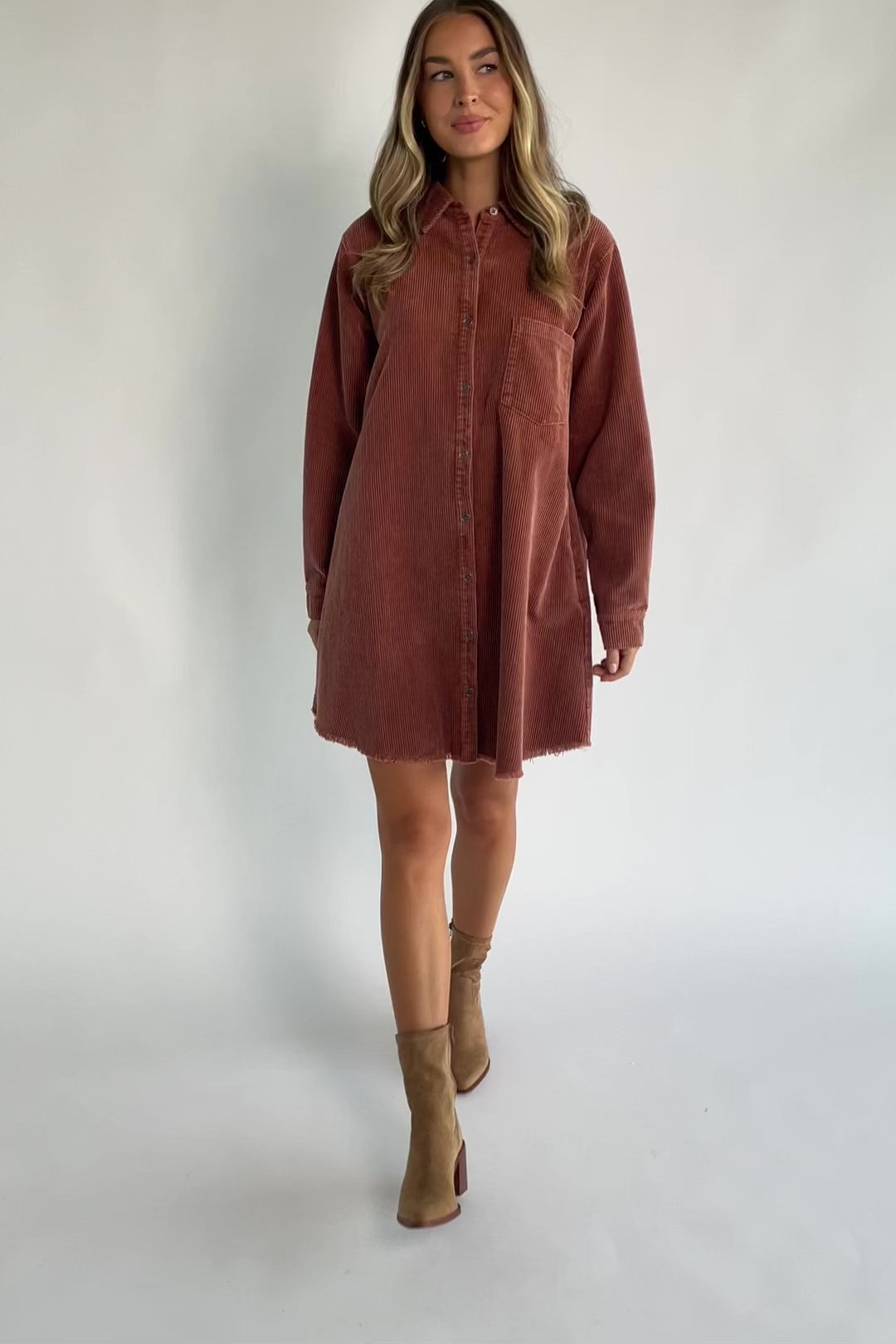 Dusty clay corduroy button-front shirt jacket with a collared neckline, oversized fit, chest pocket, long sleeves, and a rounded high-low hem.