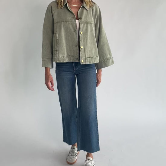 Dusty Olive Cropped Cotton Jacket with collared neckline, button front, raglan sleeves, adjustable cuffs, and side pockets.