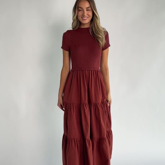 Midi dress with a ribbed knit bodice, round neckline, short sleeves, elastic waist, tiered woven skirt, and side pockets.