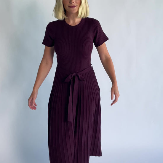 Jessamine Midi Dress in Dark Plum with a ribbed sweater knit, crew neckline, waist belt, and pleated midi skirt.