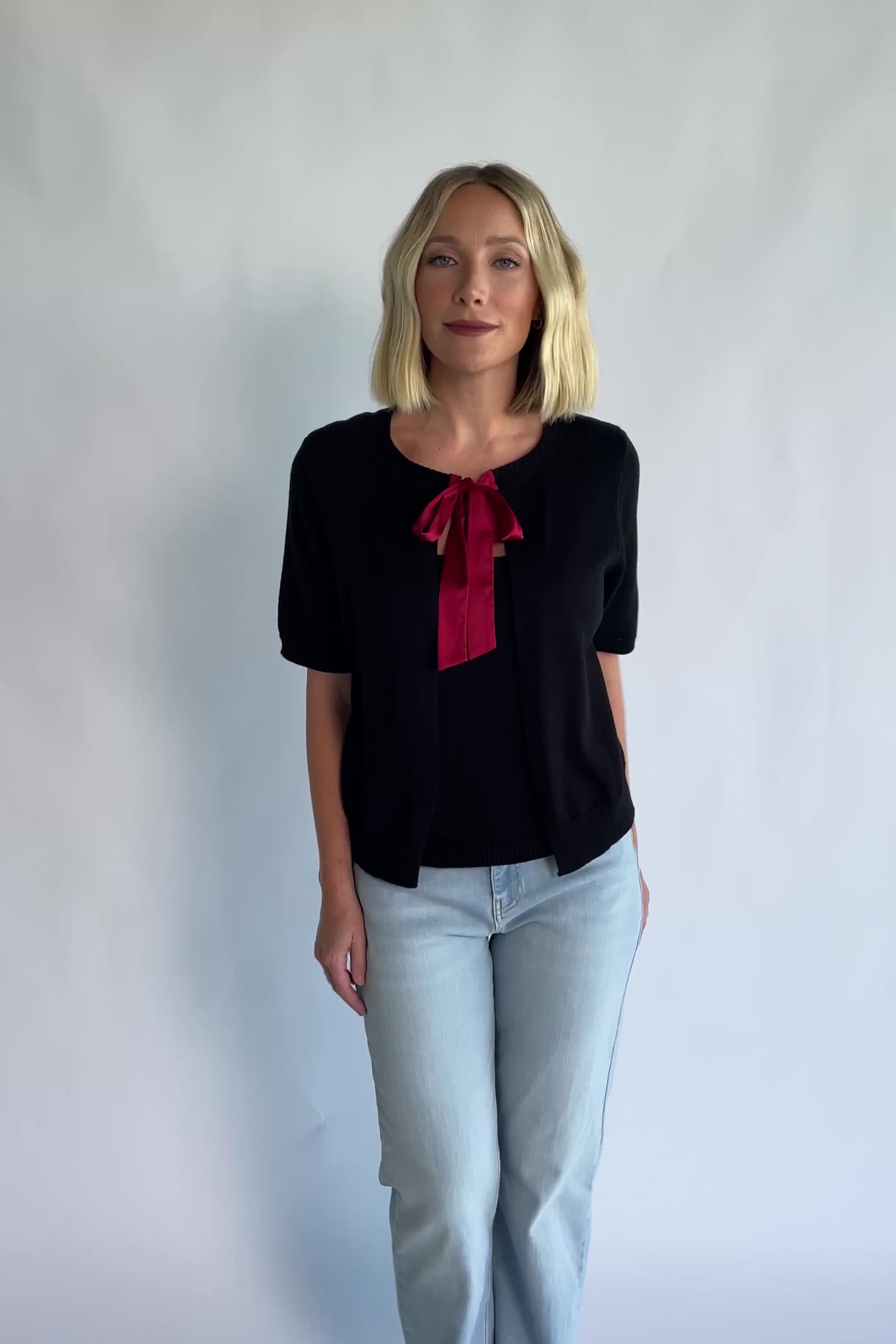 Shaye Sweater Top in Black with a built-in tank, satin bow tie closure, and soft knit construction.