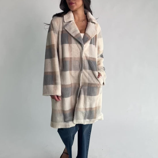 Natural plaid faux fur mid-length coat with taupe and gray accents, notched collar, hidden front snap closure, long sleeves, functional side pockets, and a fully lined interior.