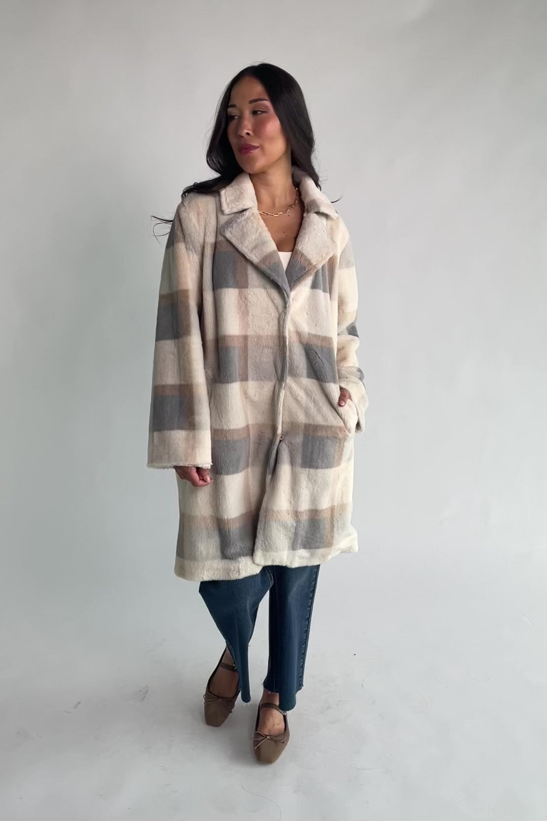 Natural plaid faux fur mid-length coat with taupe and gray accents, notched collar, hidden front snap closure, long sleeves, functional side pockets, and a fully lined interior.