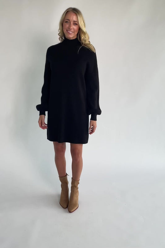 Black knit sweater dress with a mock neckline, long balloon sleeves, dropped shoulders, and a relaxed above-the-knee silhouette.