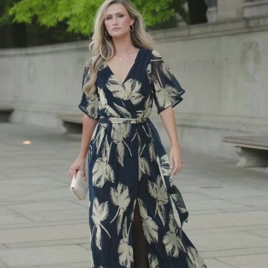 Rachel Maxi Dress in Navy + Gold with shimmer finish, surplice neckline, self-tie sash, long sleeves, and leg slit.