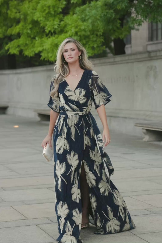 Rachel Maxi Dress in Navy + Gold with shimmer finish, surplice neckline, self-tie sash, long sleeves, and leg slit.