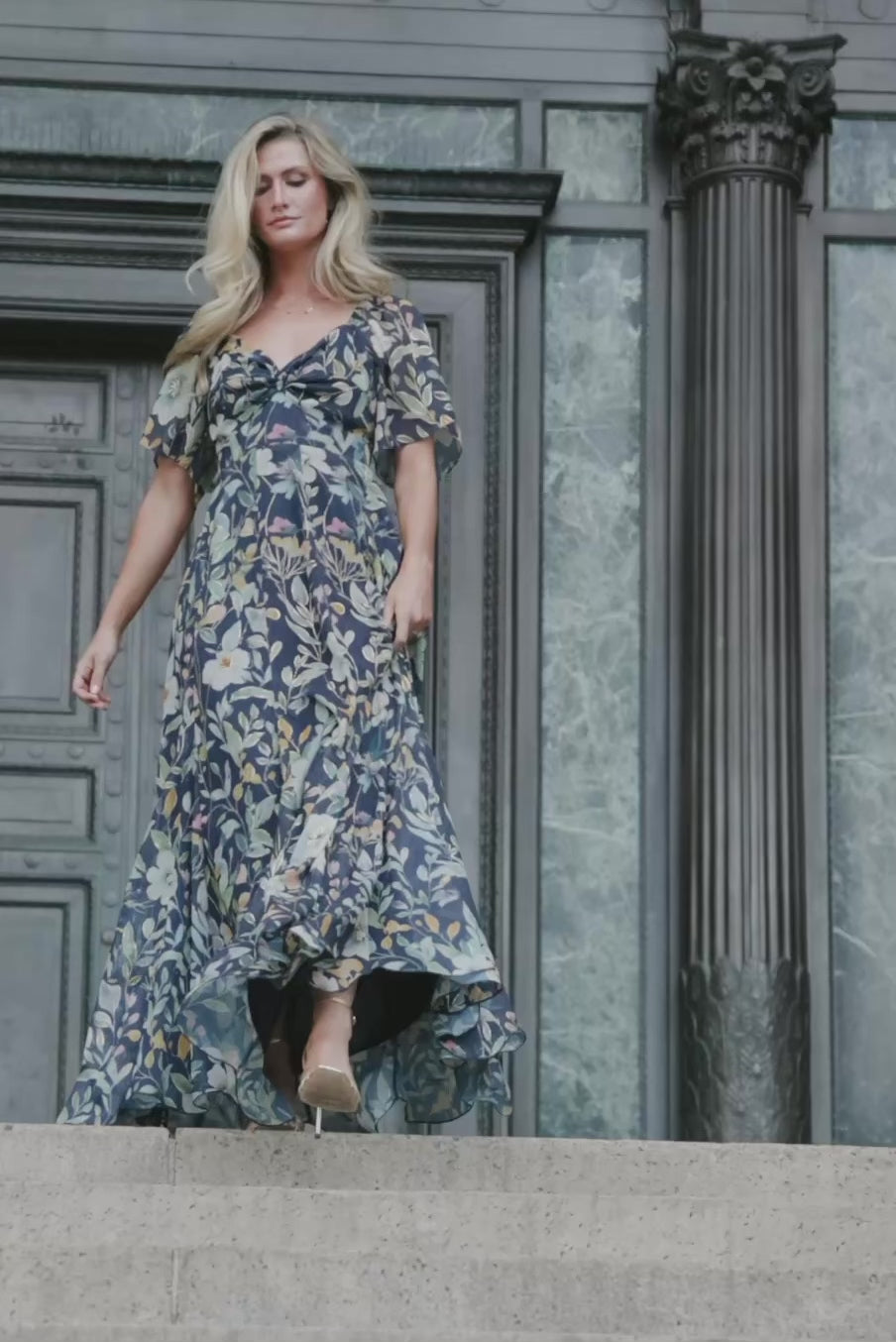 Navy floral chiffon maxi dress with a sweetheart neckline, knot detail, flutter sleeves, smocked back bodice, and a flowing tiered skirt.