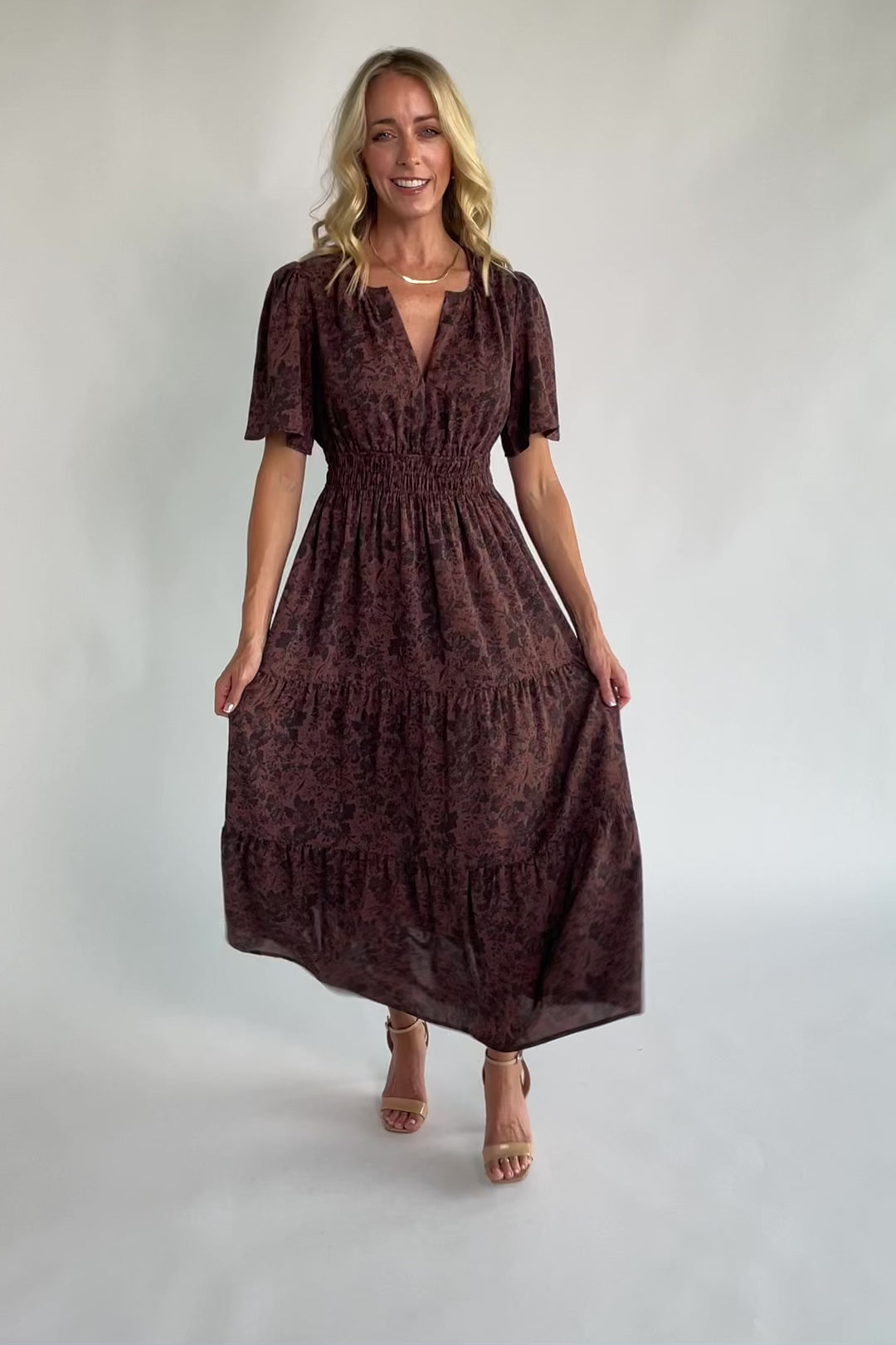 Espresso floral maxi dress with a split V-neckline, flutter sleeves, smocked waist, and flowing tiered skirt.