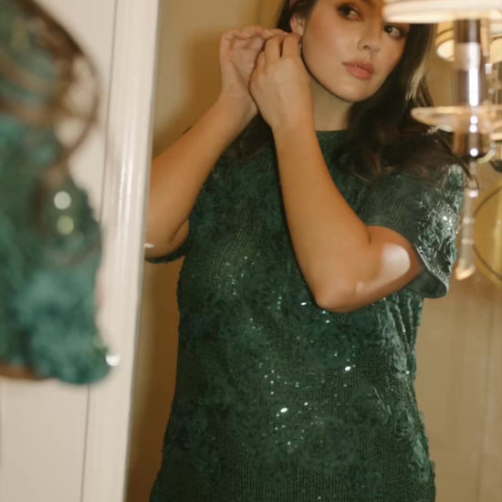Model wearing a green short shift dress embellished with green sequins and floral appliqué detailing.
