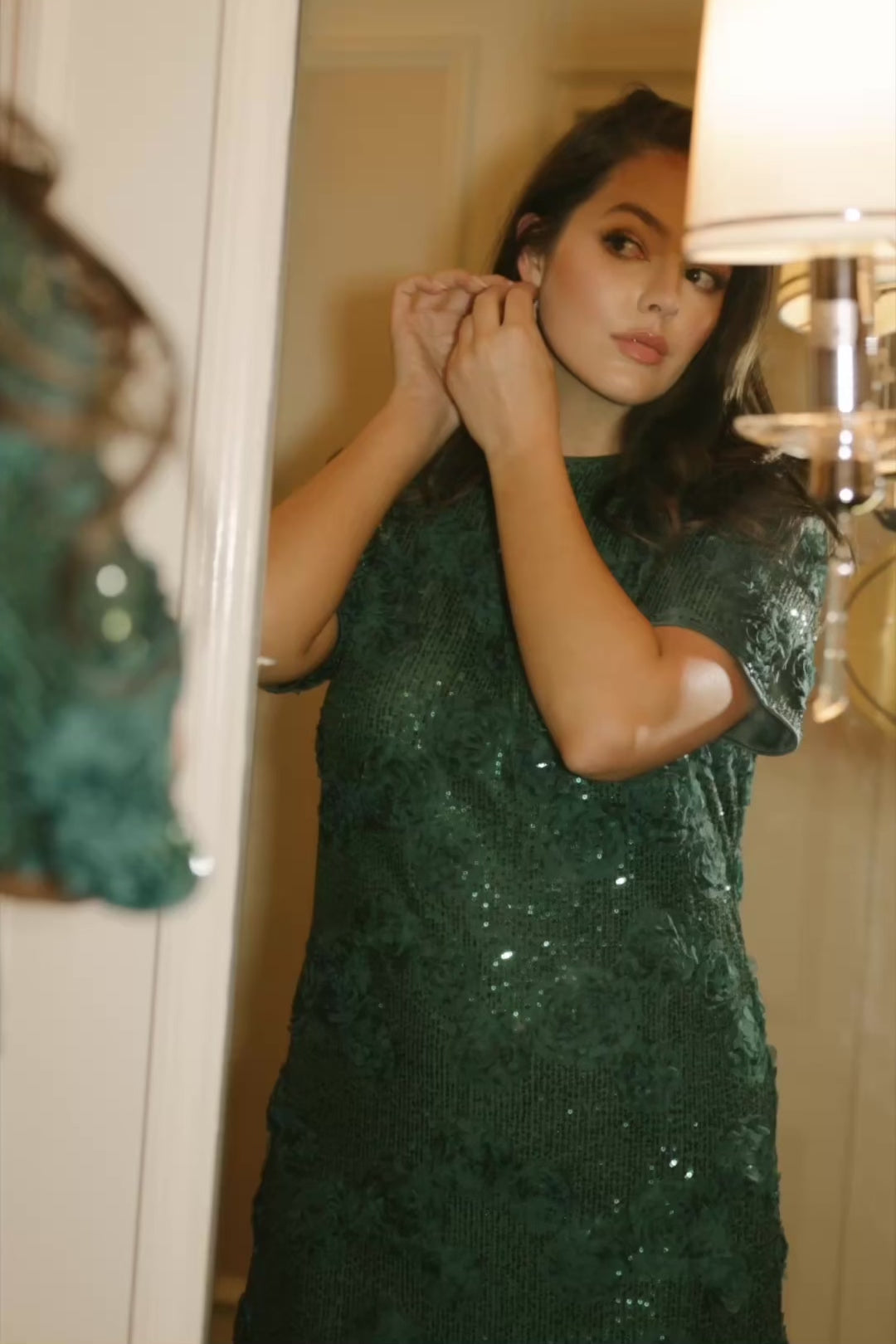 Model wearing a green short shift dress embellished with green sequins and floral appliqué detailing.