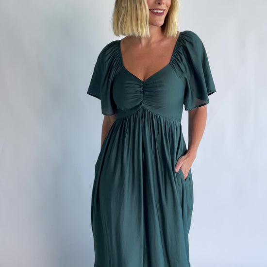 Anisa Midi Dress in Emerald with a V-neckline, cinched bust, and elastic shoulders.