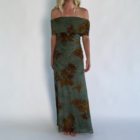 Model wearing an off-the-shoulder maxi dress with a green mesh overlay and copper velvet floral detailing.