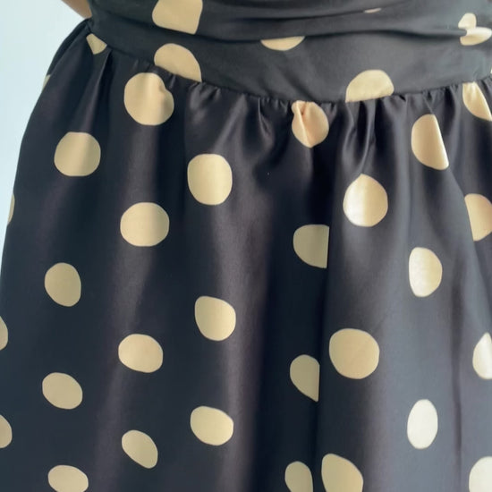 Lucienne Strapless Midi Dress in Black + Beige Dot with strapless neckline, cinched bodice, smocked back, and dropped waist.
