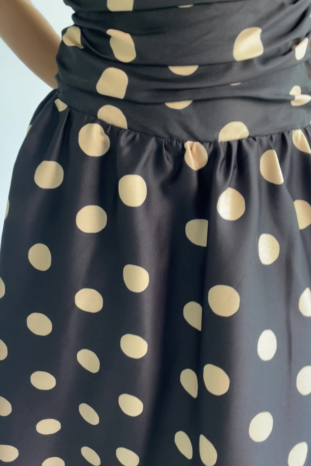 Lucienne Strapless Midi Dress in Black + Beige Dot with strapless neckline, cinched bodice, smocked back, and dropped waist.