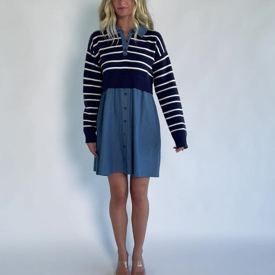 Model wearing a navy and ivory striped sweater dress with a collared neckline, functional button-front detail, long sleeves, and an elastic waist.