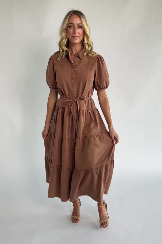 Dusty mocha midi dress with a collared neckline, gold-tone button-front closure, short puff sleeves, removable waist tie, and tiered skirt.
