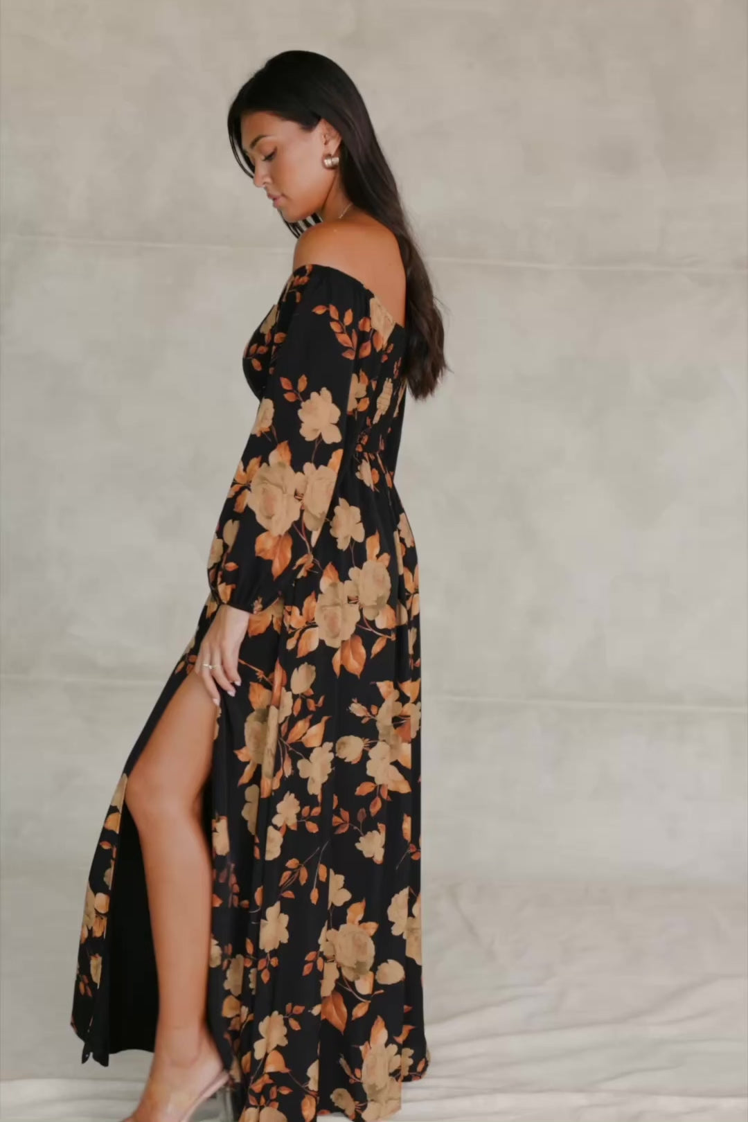 Cordelia Off Shoulder Maxi Dress in Black + Gold Floral with an off-shoulder neckline, billowy sleeves, and a leg slit.