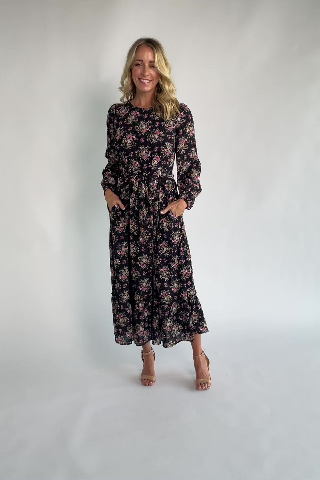 Floral midi dress with a round neckline, long sleeves, smocked back bodice, removable waist tie, tiered skirt, and back keyhole closure.
