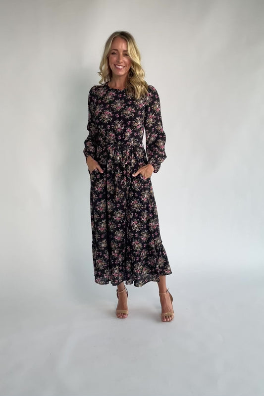 Floral midi dress with a round neckline, long sleeves, smocked back bodice, removable waist tie, tiered skirt, and back keyhole closure.