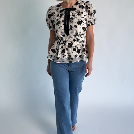 Gwenyth Peplum Blouse in Ivory + Black with velvet florals, front bow, puff sleeves, and elastic peplum waist.