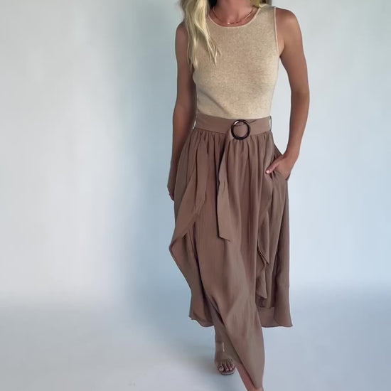 Model wearing the Stacy Midi Dress in Taupe + Mocha featuring a ribbed taupe knit bodice with a bateau neckline and a flowing woven midi skirt.